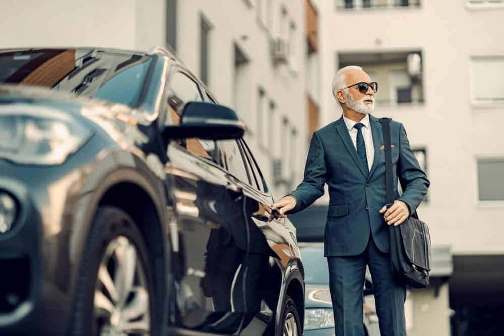 Senior businessman opening his car door, dressed professionally, arriving for a meeting or workday